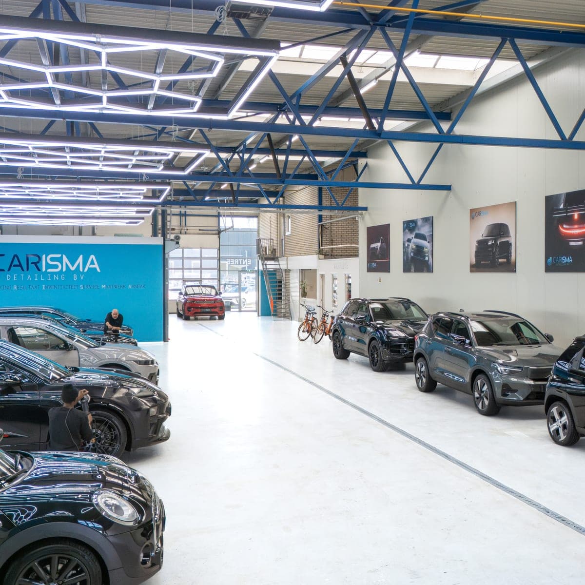 Binnenaanzicht van de werkplaatshal met meerdere auto’s op een rij