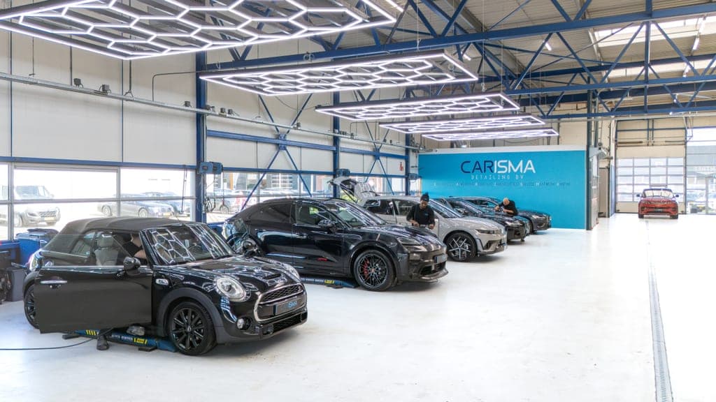 Werkplaatshal met meerdere auto’s onder hexagon-vormige LED-verlichting