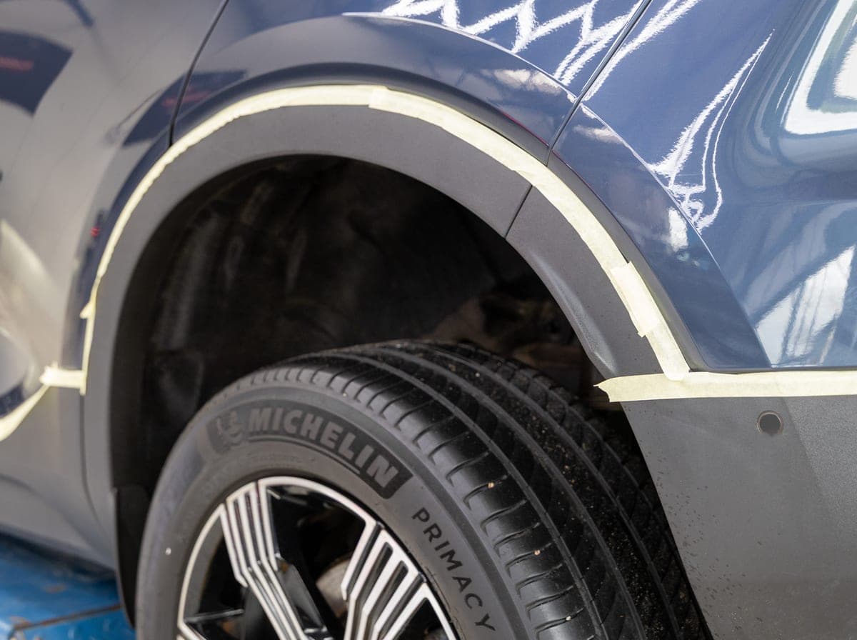 Close-up van een wielkast met afplaktape ter voorbereiding op coating