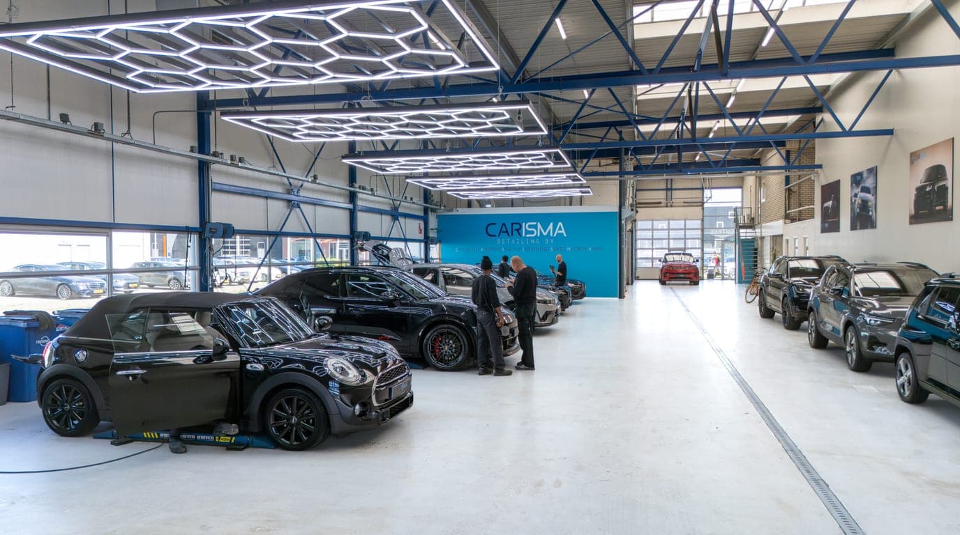 Twee medewerkers overleggen bij een auto voor de Carisma-merkwand
