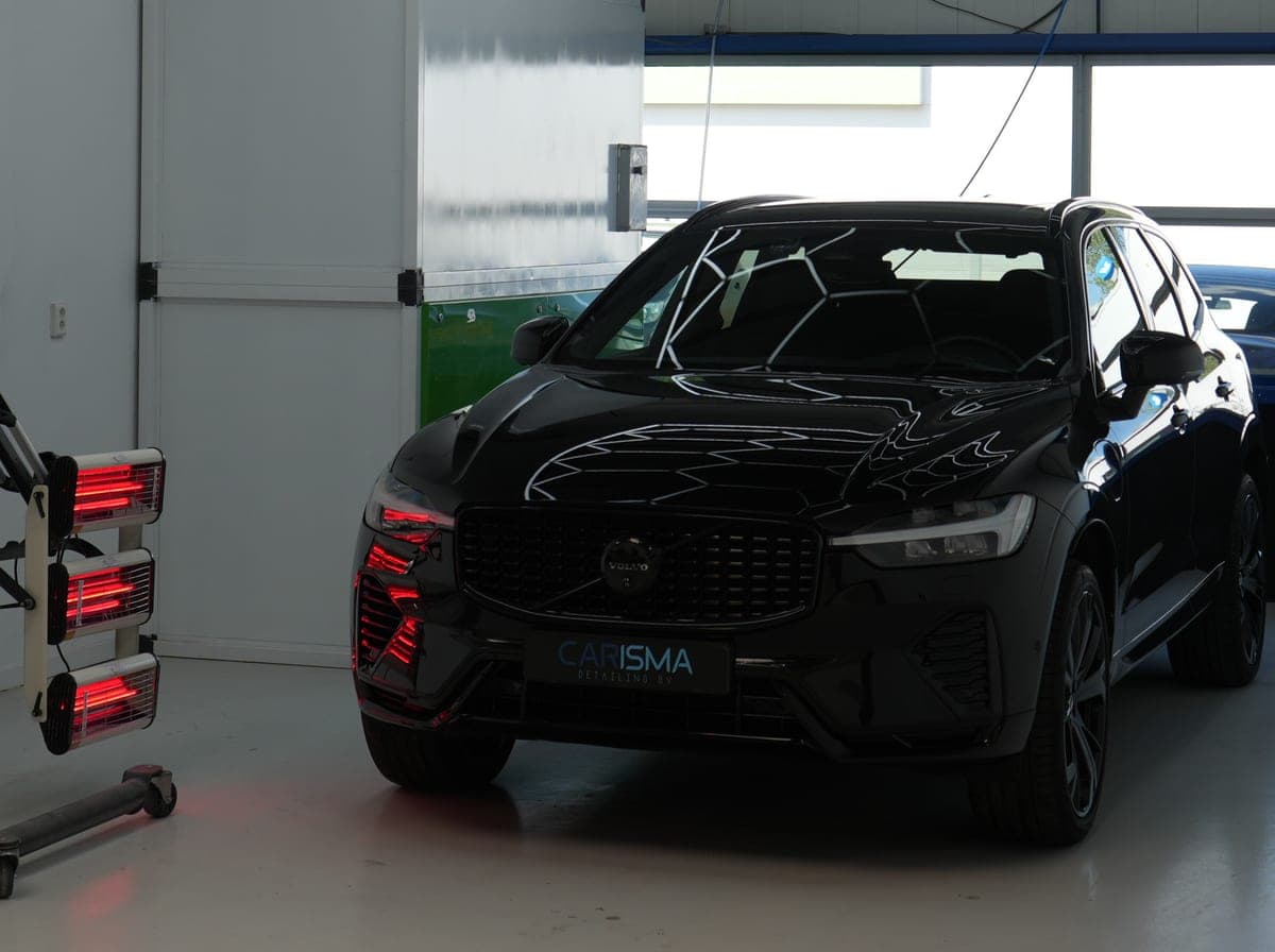 Auto met infraroodlampen tijdens een lakherstelbehandeling bij Carisma Detailing