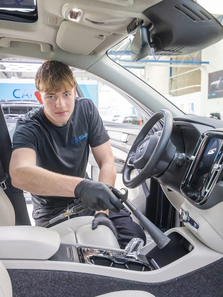 Tijs reinigt de middenconsole van een Volvo met een stoomreiniger