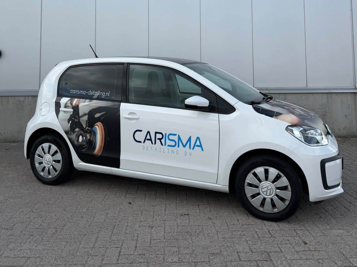 De witte leenauto van Carisma Detailing met bedrijfsbelettering, voor de gevel met de naam Carisma Detailing BV