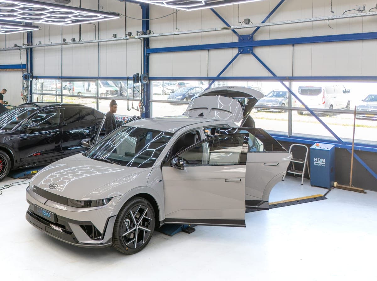 Een grijze auto met geopende portieren in de werkplaats