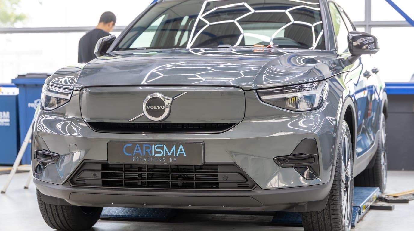 Vooraanzicht van een grijze Volvo met Carisma-kentekenplaat