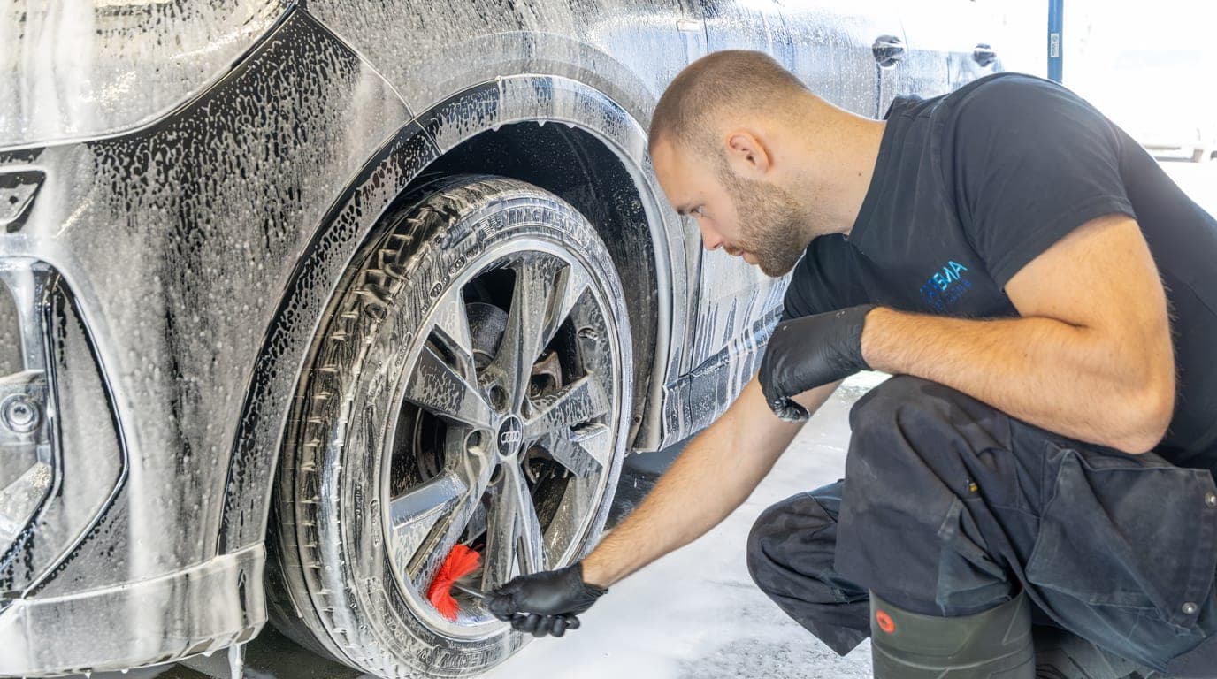 Close-up van een medewerker die een schuimende velg reinigt